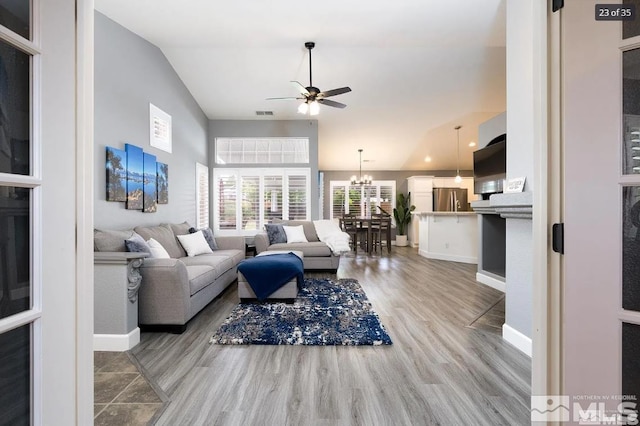 living area with visible vents, ceiling fan with notable chandelier, light wood-style flooring, and baseboards