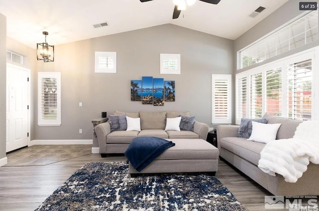 living area with visible vents, baseboards, wood finished floors, and ceiling fan with notable chandelier