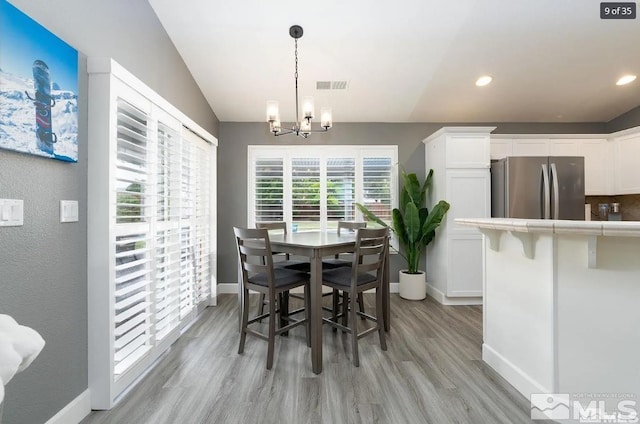 dining room with a notable chandelier, visible vents, light wood-type flooring, and baseboards