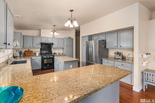 kitchen featuring an inviting chandelier, freestanding refrigerator, a sink, gray cabinetry, and black range with gas stovetop