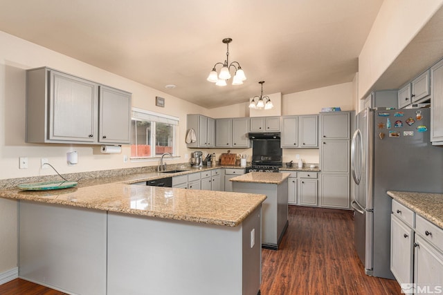 kitchen with gray cabinetry, range with gas cooktop, a chandelier, under cabinet range hood, and freestanding refrigerator