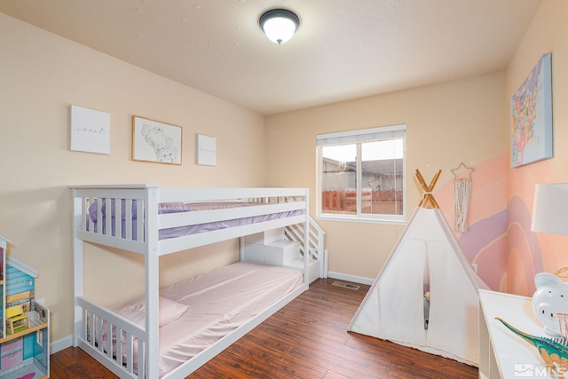 bedroom with visible vents, baseboards, and wood finished floors