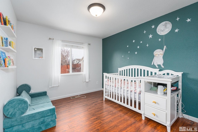 bedroom featuring visible vents, baseboards, and wood finished floors