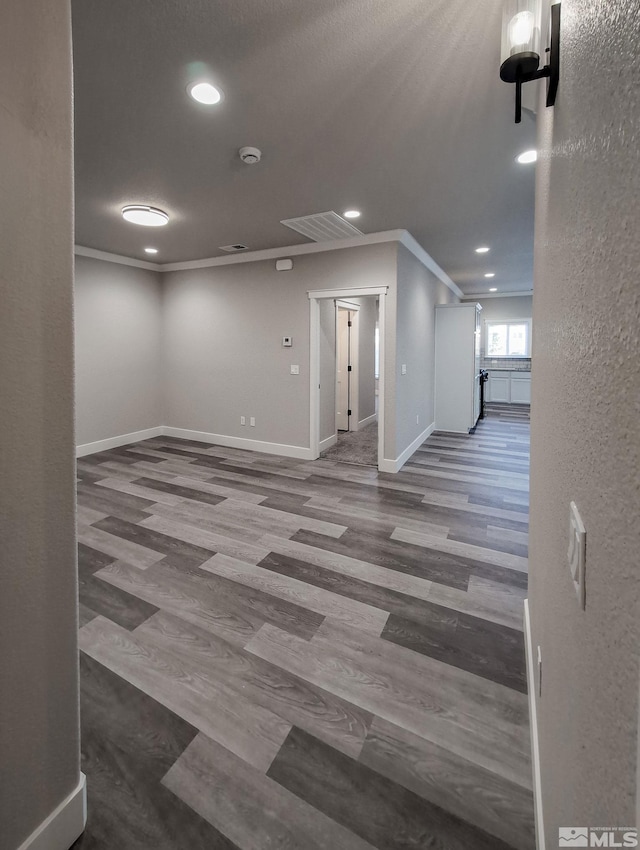unfurnished room with baseboards, wood finished floors, and crown molding