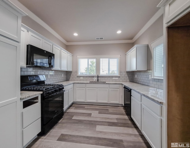 kitchen with decorative backsplash, black appliances, visible vents, and a sink