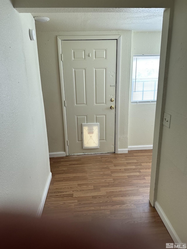 interior space with a textured wall, baseboards, and wood finished floors