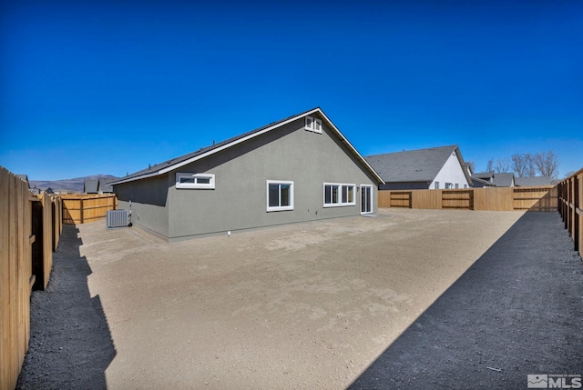 back of house with stucco siding, central AC unit, and a fenced backyard
