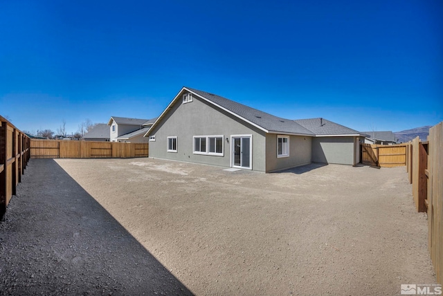 rear view of house featuring a fenced backyard and stucco siding