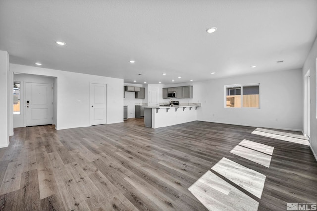 unfurnished living room with recessed lighting, baseboards, and wood finished floors