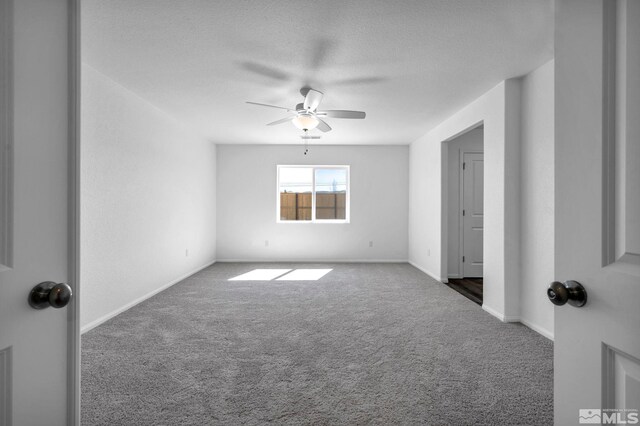 carpeted empty room with a textured ceiling, baseboards, and ceiling fan