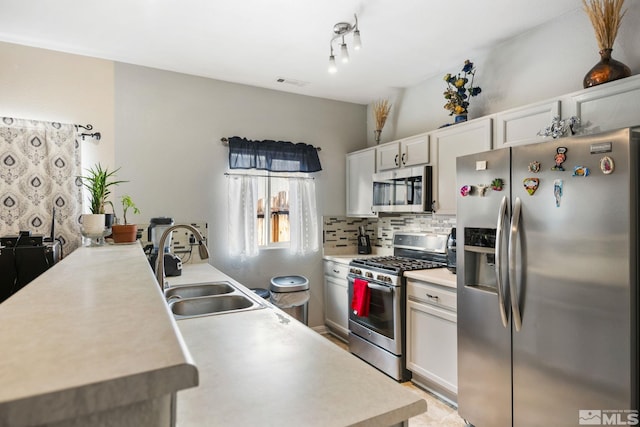 kitchen featuring visible vents, light countertops, decorative backsplash, stainless steel appliances, and a sink
