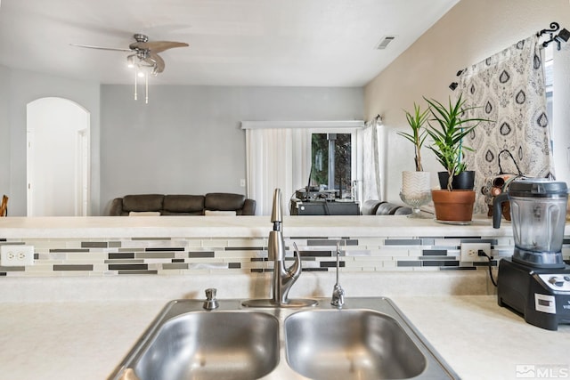 kitchen featuring tasteful backsplash, visible vents, arched walkways, a ceiling fan, and a sink