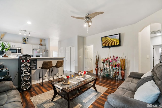 living room featuring arched walkways, wood finished floors, and a ceiling fan