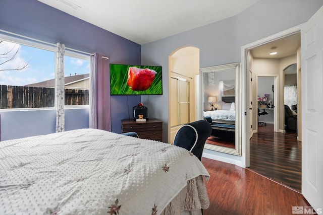 bedroom with visible vents, arched walkways, dark wood-type flooring, and baseboards
