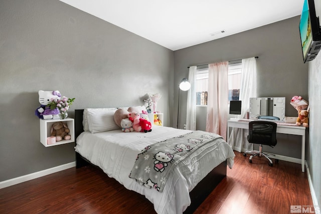 bedroom featuring visible vents, baseboards, and wood finished floors