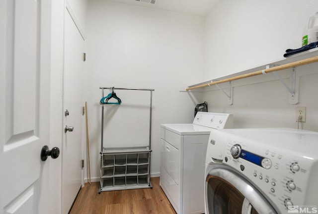 laundry room with visible vents, washing machine and dryer, laundry area, and light wood finished floors