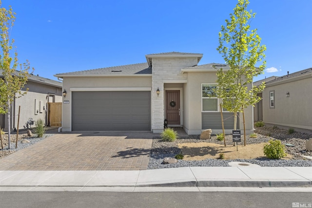 view of front facade featuring decorative driveway, an attached garage, and stucco siding