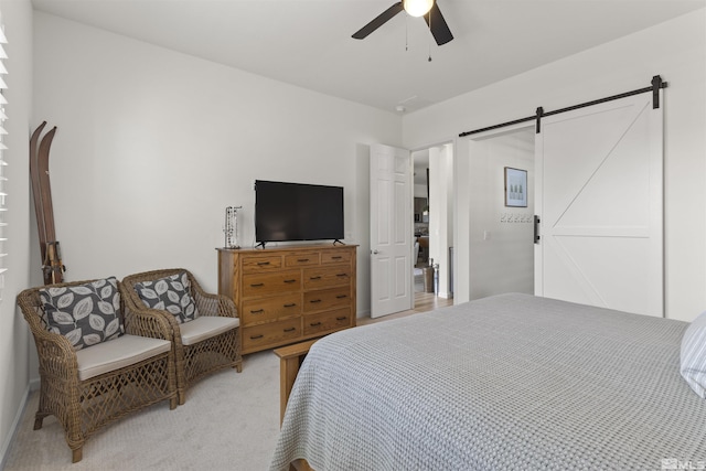 bedroom featuring a barn door, a ceiling fan, and light carpet