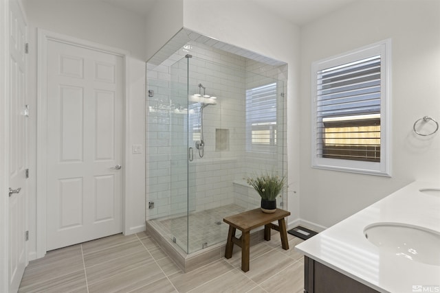 full bathroom with a sink, baseboards, a stall shower, and double vanity