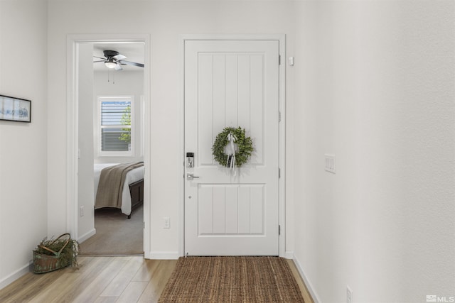 foyer with baseboards, wood finished floors, and ceiling fan