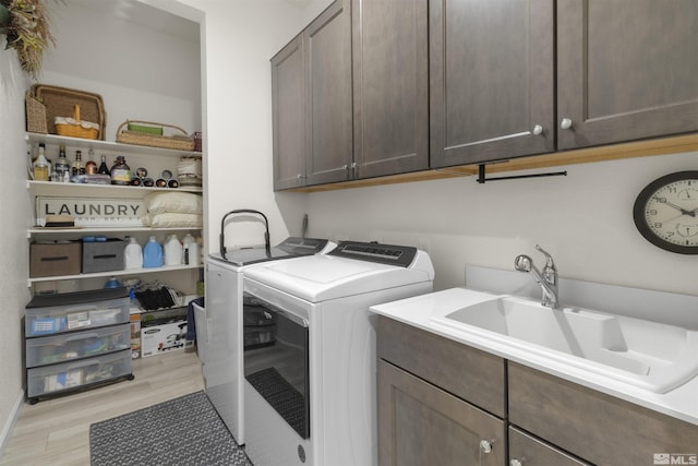 washroom with light wood-style floors, cabinet space, independent washer and dryer, and a sink