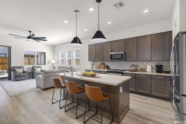 kitchen featuring visible vents, a ceiling fan, tasteful backsplash, dark brown cabinetry, and appliances with stainless steel finishes