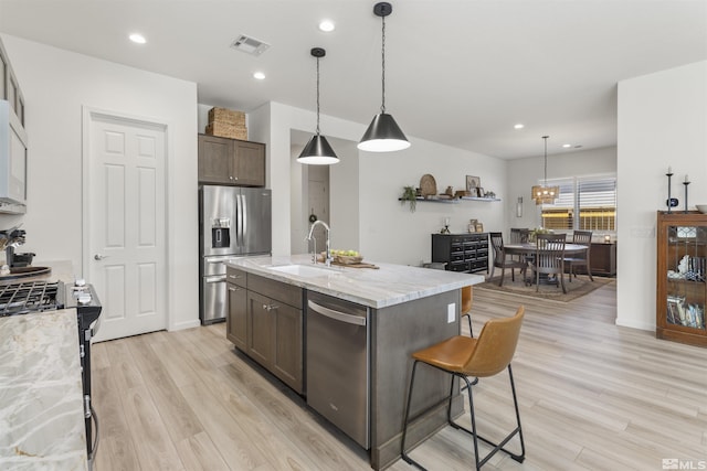 kitchen with visible vents, a sink, stainless steel appliances, dark brown cabinetry, and light wood-style floors
