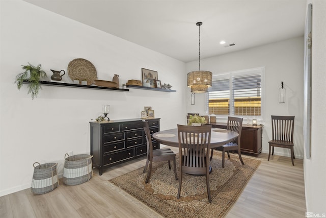 dining space with light wood-style floors, visible vents, and baseboards