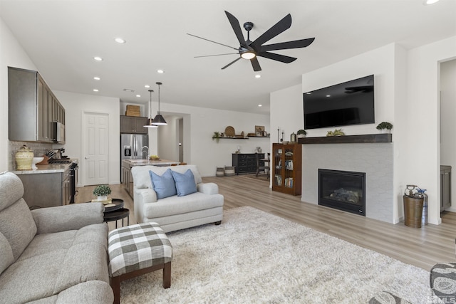 living room with a fireplace, recessed lighting, light wood-style floors, and ceiling fan