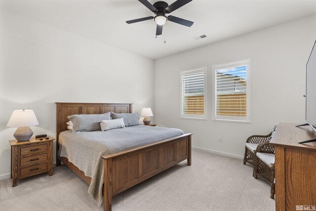 bedroom with visible vents, light colored carpet, baseboards, and ceiling fan