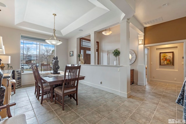tiled dining space featuring a tray ceiling, visible vents, and baseboards