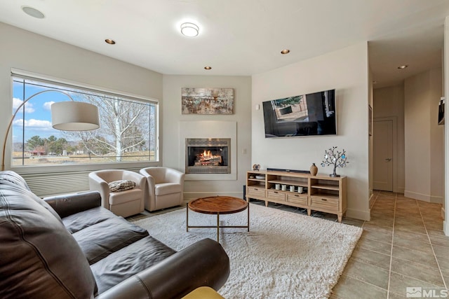 living room featuring recessed lighting, baseboards, a glass covered fireplace, and light tile patterned flooring