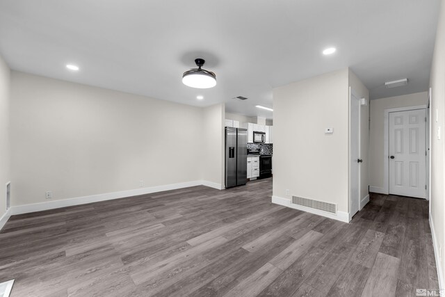 unfurnished living room with visible vents, baseboards, and dark wood finished floors