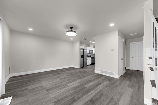 unfurnished living room with dark wood finished floors, visible vents, recessed lighting, and baseboards