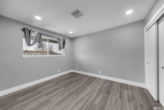 unfurnished bedroom featuring a closet, visible vents, baseboards, and wood finished floors