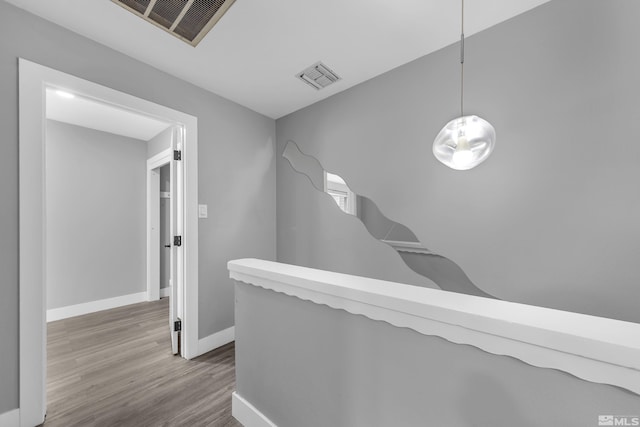 corridor featuring wood finished floors, visible vents, and baseboards