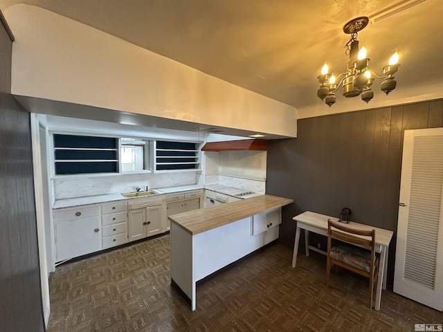 kitchen featuring a peninsula, open shelves, white cabinets, dark floors, and a chandelier