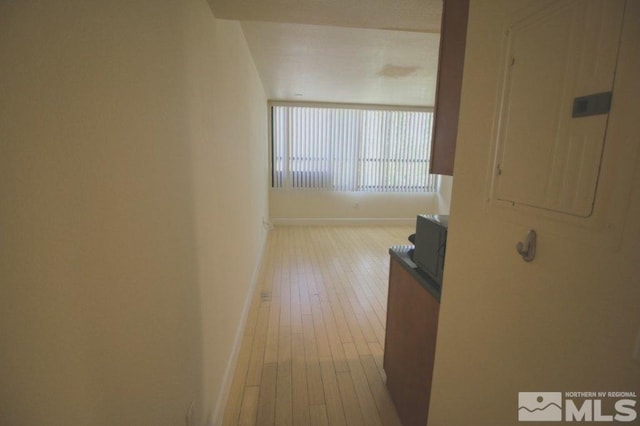 corridor with electric panel, hardwood / wood-style flooring, and baseboards