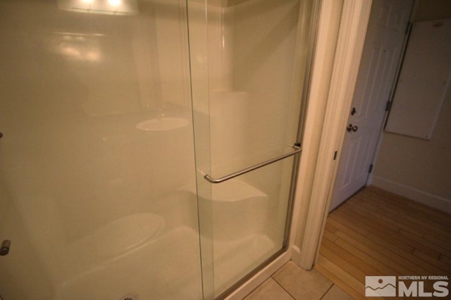bathroom with baseboards, tile patterned flooring, and a stall shower