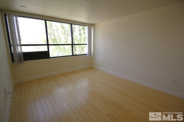 empty room featuring baseboards and light wood-style floors