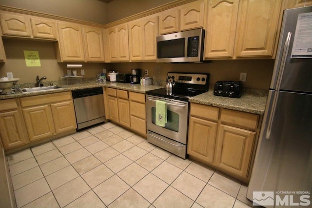kitchen featuring appliances with stainless steel finishes, a sink, light brown cabinetry, and light tile patterned floors