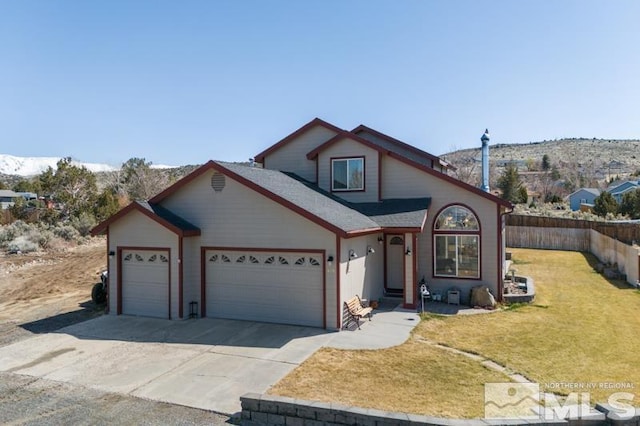 traditional-style home featuring an attached garage, driveway, a front lawn, and fence