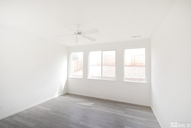 empty room with baseboards, visible vents, wood finished floors, and a ceiling fan