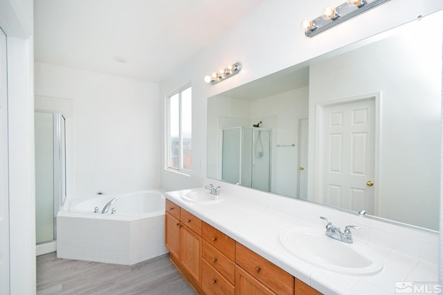 full bathroom with a shower stall, double vanity, a sink, and a garden tub