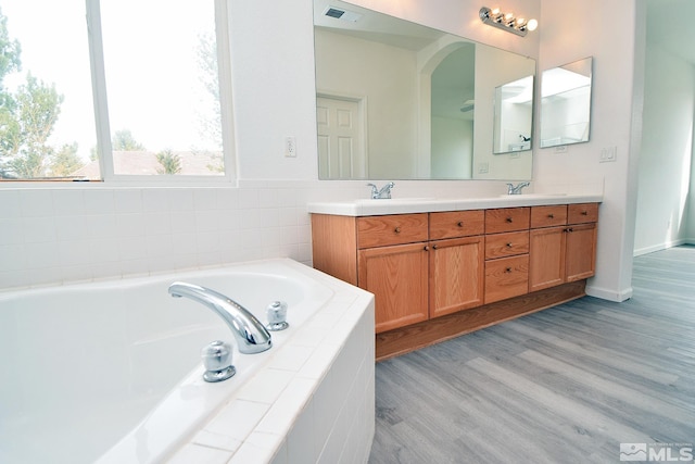 full bath with a sink, double vanity, visible vents, and a garden tub