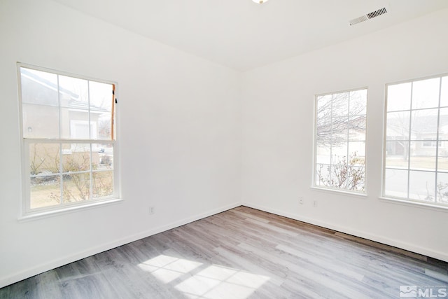 unfurnished room featuring wood finished floors, baseboards, and visible vents