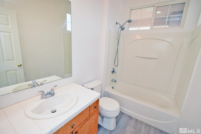 bathroom with wood finished floors, toilet, vanity, and washtub / shower combination