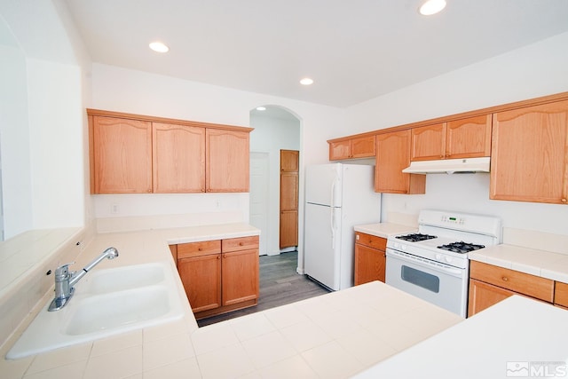 kitchen with under cabinet range hood, a sink, recessed lighting, and white appliances