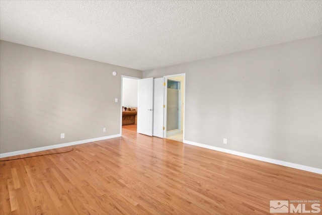 unfurnished room featuring a textured ceiling, baseboards, and light wood-style floors