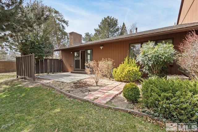 back of property with a patio, fence, a chimney, entry steps, and a lawn